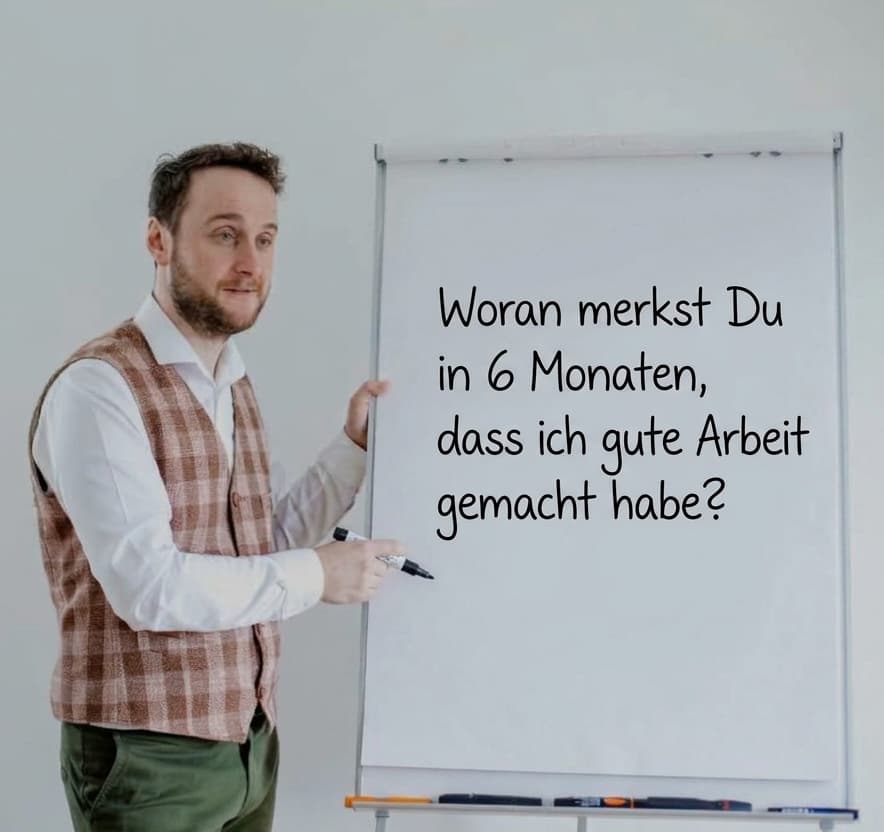 Coach steht vor einem Flipchart und fragt nach der erwarteten Wirkung in 6 Monaten.