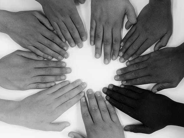 8 hands of people on a table, symbolizing shared responsibility